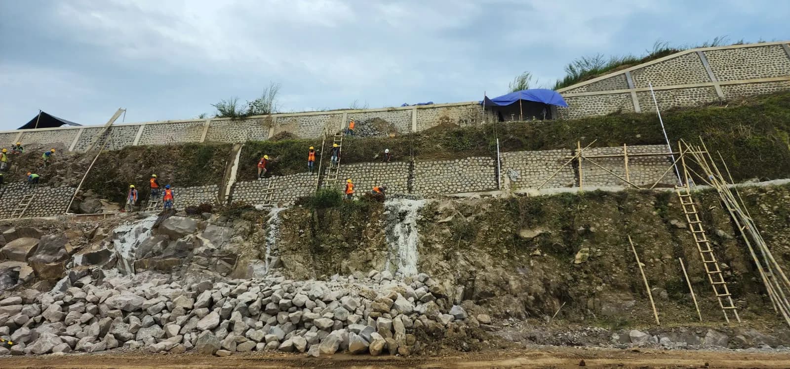 Pekerja membangun dinding penahan tanah di lereng
