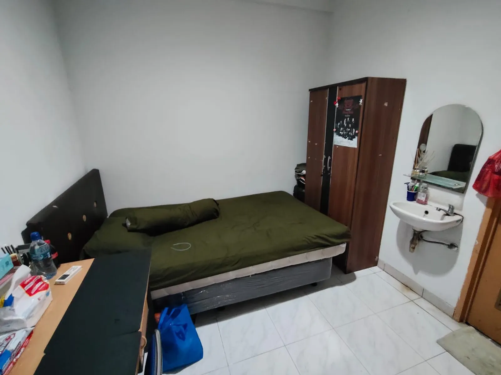 Kamar kos dengan kasur, lemari, dan wastafel