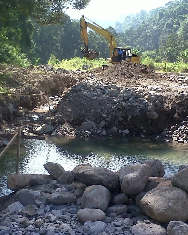 Pekerjaan saluran sungai dengan ekskavator dan susunan batu